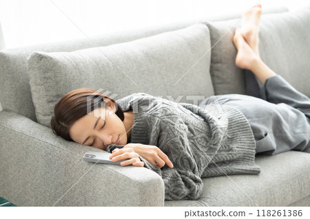 A woman lying down and looking at a smartphone A woman lying down and looking at a smartphone 118261386