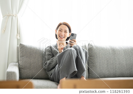 一位女士坐在沙發上操作智慧型手機，指著 118261393