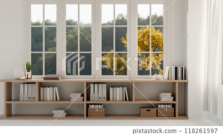 A front view of a lower bookcase against the window in a bright contemporary Scandinavian room. A front view of a lower bookcase against the window in a bright contemporary Scandinavian room. 118261597