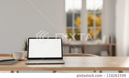 A laptop with a white screen mockup on a wooden tabletop in a contemporary minimalist room. 118261599