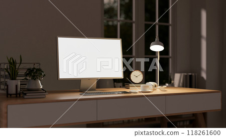 A contemporary home workspace at night features a computer on a minimalist wooden table. 118261600