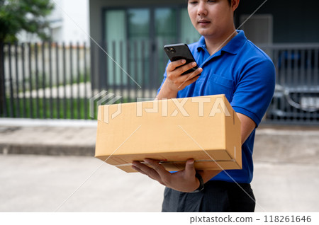 A delivery guy is taking a picture of a package before delivering it in front of a customer's house. 118261646
