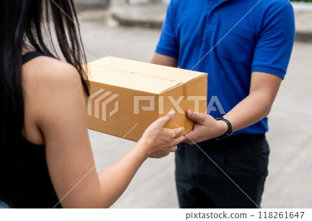 A cropped image of a customer receiving a package from a delivery man in front of her house. A cropped image of a customer receiving a package from a delivery man in front of her house. 118261647