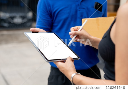 A customer signing on a tablet before receiving her package from a delivery man. A customer signing on a tablet before receiving her package from a delivery man. 118261648