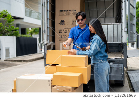 A delivery guy is confirming the packages with a female customer at the back of his truck. 118261669