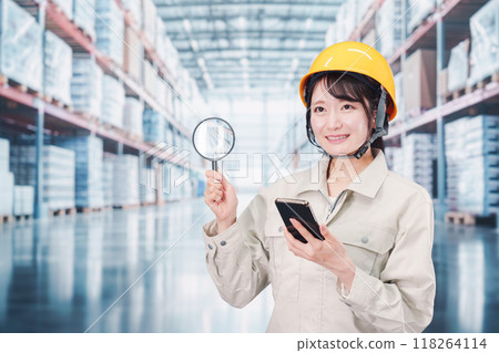 A woman in work clothes searching for inventory in a warehouse 118264114