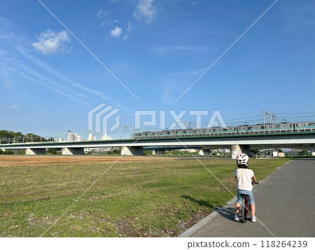 A child riding a bicycle is looking at the train 118264239