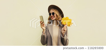 Autumn portrait stylish happy smiling young woman with phone, beautiful girl holding yellow leaves Autumn portrait stylish happy smiling young woman with phone, beautiful girl holding yellow leaves 118265800