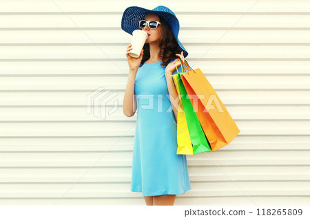beautiful happy young woman with coffee cup and shopping bags in blue dress, summer hat on white beautiful happy young woman with coffee cup and shopping bags in blue dress, summer hat on white 118265809