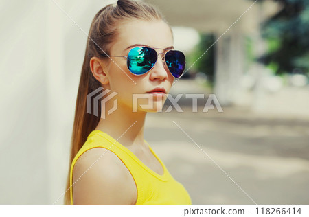 Portrait close up of beautiful young woman wearing a sunglasses posing in a city 118266414