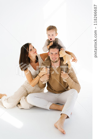 Mother and father hold their two year old son and a teddy bear in their arms Mother and father hold their two year old son and a teddy bear in their arms 118266687