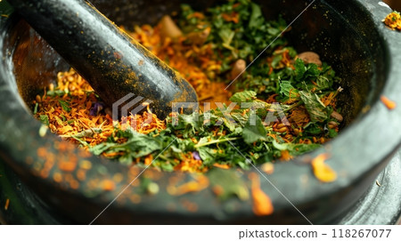 Close-up of a mortar and pestle with vibrant Ayurvedic herbs, ground and ready for holistic healing. 118267077