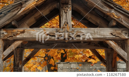 A rustic, weathered entablature with hand-carved details stands against a backdrop of golden autumn leaves. 118267580