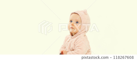 Happy cute baby sitting on the floor looking up in soft clothing on white studio background 118267608