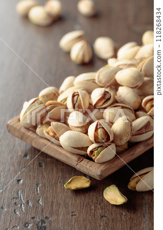 Salted pistachios on an old wooden table. 118268434