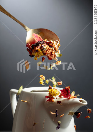 Dried herbs and flowers is poured into a white teapot. Dried herbs and flowers is poured into a white teapot. 118268543