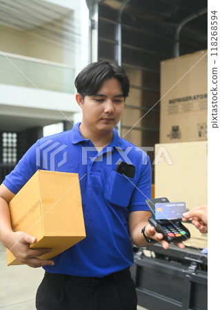 Delivery man delivering a package to a customer and receiving payment with credit card 118268594