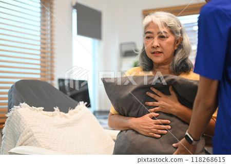 Physical therapist doing back percussion on a senior patient to help loosen and drain secretions from her lungs 118268615