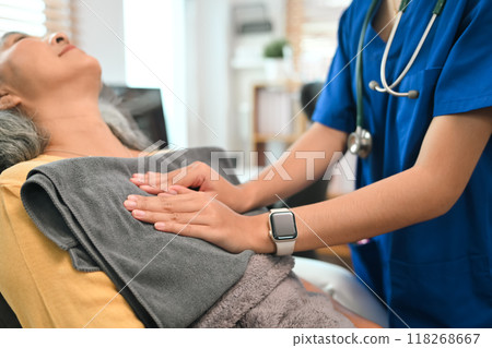 Physical therapist doing chest percussion on a senior patient to help loosen and drain secretions from her lungs 118268667