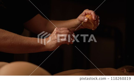 Use of oranges during massage. Female therapist using orange during back massage at the spa. Oranges are squeezed on the female body during the massage. Use of oranges during massage. Female therapist using orange during back massage at the spa. Oranges are squeezed on the female body during the massage. 118268819