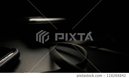 Smartphone cord from the charger on the table on a black background. Wires from the charger to the phone on a black background close-up. Smartphone cord from the charger on the table on a black background. Wires from the charger to the phone on a black background close-up. 118268842