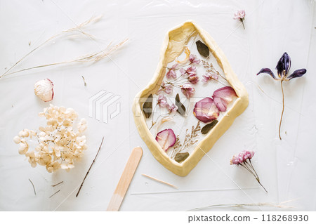 Pressed flowers arranged in resin mold, showcasing the transformation of everyday materials into DIY art. Eco-friendly crafting techniques for home decor. 118268930