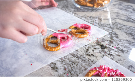 With focused attention, this budding culinary artist dips pretzels into a pot of melted chocolate, creating sweet delights in the warmth of a well-lit home kitchen. With focused attention, this budding culinary artist dips pretzels into a pot of melted chocolate, creating sweet delights in the warmth of a well-lit home kitchen. 118269300