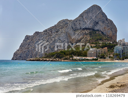 Breathtaking Costa Blanca Paradise: Calpe's Pristine Beach and Iconic Rock of Ifach Rock Formation Overlooking Azure Mediterranean Waters. Spanish Riviera: Calpe's Golden Sands and Majestic Ifach Rock 118269479