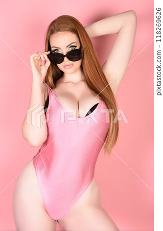 Attractive young woman in a swimsuit and sunglasses Attractive young woman in a swimsuit and sunglasses 118269626
