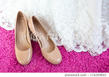 Elegant Nude Heels Beside Lace Wedding Dress on Pink Rug in Bright Setting. 118269683