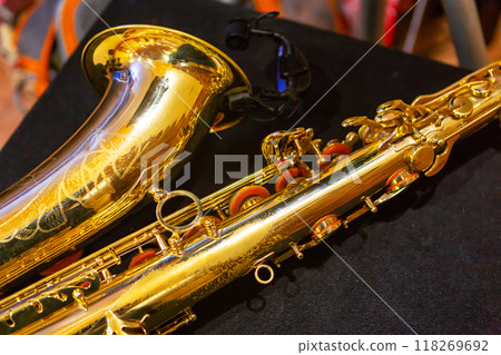 Golden Saxophone Resting on a Black Surface With a Blurred Background. Golden Saxophone Resting on a Black Surface With a Blurred Background. 118269692