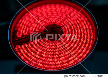 Close-up of a hob with electric hot plates: the heating elements are bright red. Selective focus on the heating elements. Concept of energy consumption and heat. Close-up of a hob with electric hot plates: the heating elements are bright red. Selective focus on the heating elements. Concept of energy consumption and heat. 118270045
