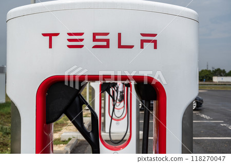 Highway to Budapest, Hungary. August 24, 2022. Tesla fast charging stations in a rest area. In the background a car is refueling. Close-up on a charging station. Highway to Budapest, Hungary. August 24, 2022. Tesla fast charging stations in a rest area. In the background a car is refueling. Close-up on a charging station. 118270047