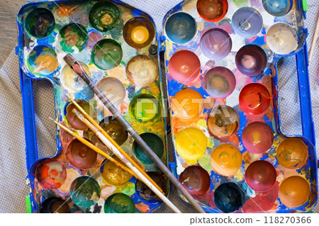 Top view of palette of paints and brushes in the process of work 118270366