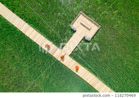 From above, the scene is serene as a Buddhist monk walks across a verdant rice field. Shot topview from Drone. From above, the scene is serene as a Buddhist monk walks across a verdant rice field. Shot topview from Drone. 118270469