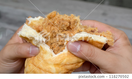 Watch as the man expertly holds and shreds a fluffy bun, revealing the juicy, succulent shredded pork hidden within. The smell of the freshly cooked pork wafts through the air 118270502