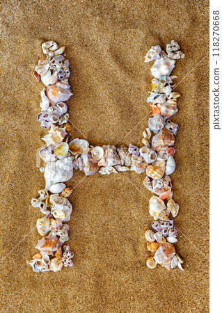 The letter H of the English alphabet, a letter made of seashells on the sand. 118270668