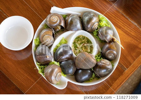Brown shelled sweet snails Put them on a white platter alongside some more vegetables. Consume seafood sauce. 118271009