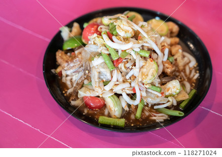 Spicy salad that is colorful and tasty, with pickled fish, long beans, bean sprouts, pork caps, crispy fish, tomatoes, and pepper. Ready to eat on wood pink table. 118271024
