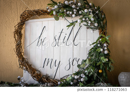 Christmas heart wreath with holly, mistletoe, ivy, pine cones and cedar leaf sprigs over white background. 118271063