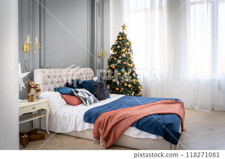 A spacious white light bedroom in a loft style with a decorated Christmas tree and a garland. 118271081