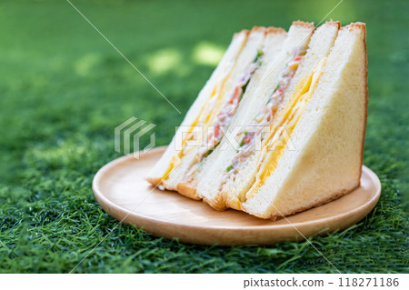 Homemade Sandwich, fried egg with crab stick, vegetable salad and mayonnaise served on a circular wooden dish. 118271186