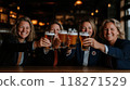 Group of cheerful women in business suits raising their glasses of beer, smiling and clinking glasses to celebrate successfully completed project, deal. 118271529