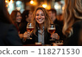 Group of women in business suits raising glasses of beer, smiling at cozy bar with soft, warm lighting 118271530