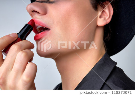 close-up androgynous man with party make-up applying pomade lipstick, isolated 118273071