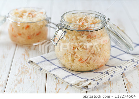 glass storage jar with sauerkraut and carrots on white kitchen table. 118274504