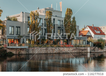 River On Sunset. Townhouses Buildings And Multi-floor Home At Waterfront. Sunset On River In City. Suburb Houses And Residential Building Near River In Europe. House In Nature On Shore On Sunset. 118277018
