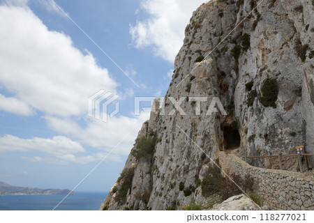 Majestic Sea Cave Entrance Carved into Rugged Coastal Cliffs Revealing Azure Waters and Endless Sky Beyond 118277021