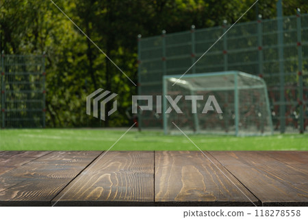 Empty wood table top with blurred outdoor football or soccer field. Abstract background. Mock up for montage product display or design your products. Empty wood table top with blurred outdoor football or soccer field. Abstract background. Mock up for montage product display or design your products. 118278558