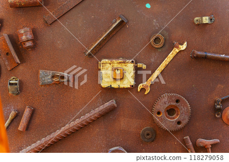 A collection of rusty metal components is resting on a rusty surface A collection of rusty metal components is resting on a rusty surface 118279058